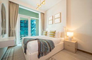Habitación de hotel con cama, mesita de noche y vista a una piscina a través de un ventanal.