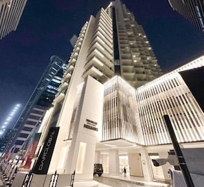 A modern high-rise building with a prominent entrance and vertical lines on the facade.