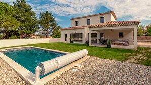 Une maison moderne à deux étages, dotée d’une piscine, d’un patio couvert et d’une pelouse bien entretenue.