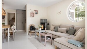 A cozy living room with a fireplace, a round window, and a dining area with a table and chairs. - Lovely home in Tranekær with WiFi (Tranekær)
