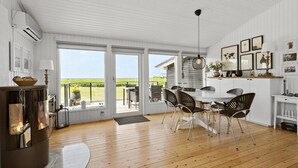 A spacious room with a large dining table, chairs, and a view of the outdoors. There is a fireplace, a ceiling fan, and a window with blinds. - 2 bedroom amazing home in Martofte (Martofte)