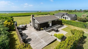 A coastal house with a deck, a small garden, and a view of the sea. - 2 bedroom amazing home in Martofte (Martofte)