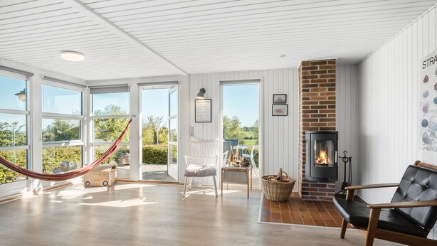 Ein geräumiger Raum mit großem Fenster, Kamin, Hängematte und einer gemütlichen Sitzecke.