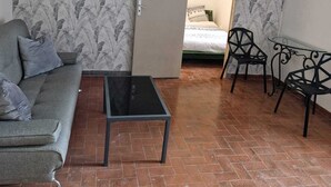 A living room with a sofa, a coffee table, and two chairs. There is a bed in the background. - Room for rent in a quiet house in the countryside (Bédarrides)