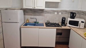 A compact kitchen with white cabinets, a sink, a stove, a microwave, and a refrigerator. - Room for rent in a quiet house in the countryside (Bédarrides)