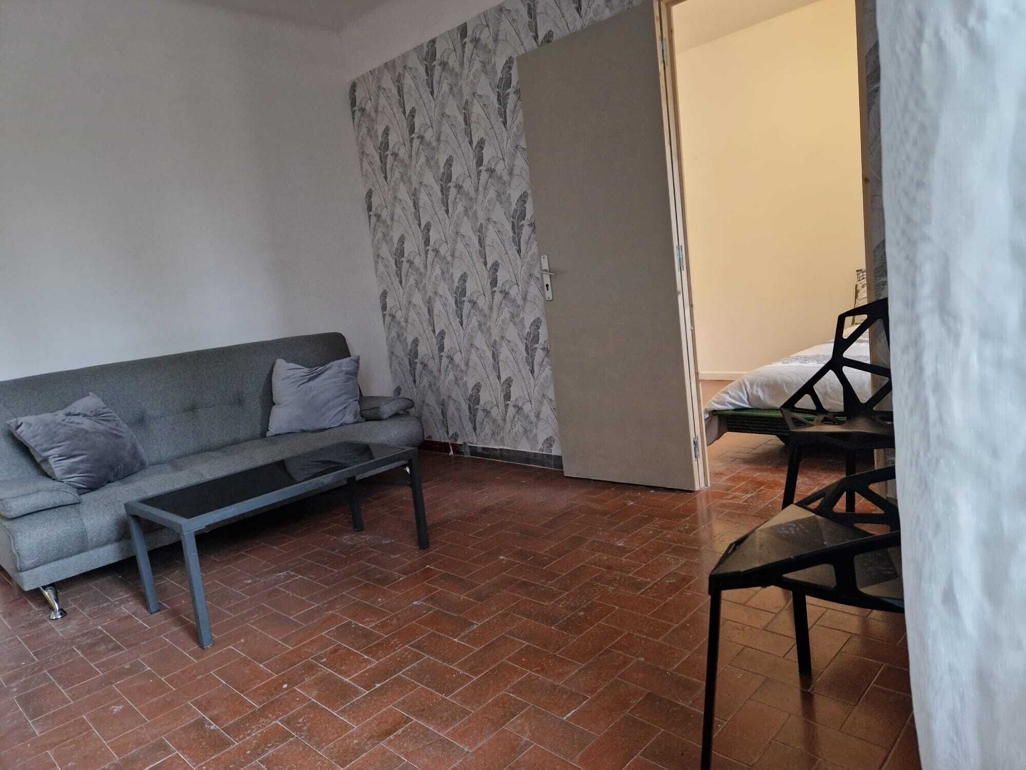 Ein Wohnzimmer mit grauem Sofa, einem kleinen Couchtisch und einer Wand mit Muster.