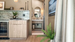 Un baño moderno con encimera de mármol, armarios de madera, un espejo grande y una planta en maceta.