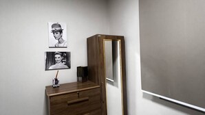 A room with a wooden dresser, a large mirror, and two framed pictures on the wall.