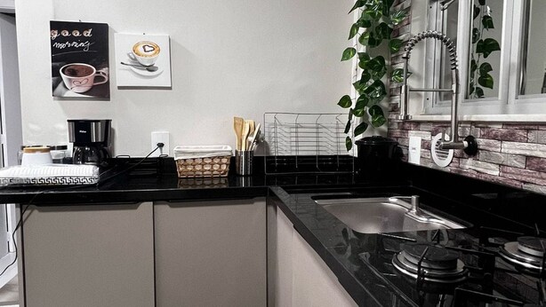 A modern kitchen with a black countertop, stainless steel appliances, and a patterned floor.