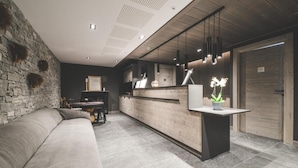Un interior moderno con pared de piedra, mostrador de recepción de madera, un sofá y un comedor.