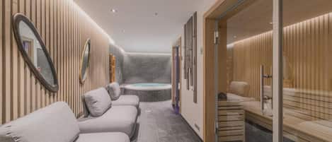Un moderno espacio de spa con cabina de masajes, zona de relajación con bancos y una bañera de hidromasaje visible.