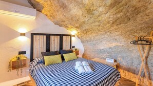 Ein Schlafzimmer mit kariertem Bettbezug, Holz-Kopfteil und zwei Wandleuchten.