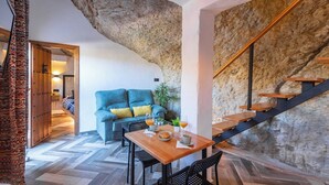 Ein gemütliches Interieur mit einer Holztreppe, einem blauen Sofa und einem Esstisch, gedeckt mit einem Glas Orangensaft und einer Teller mit Essen.