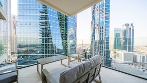Un balcón moderno con un sofá y una silla, que ofrece vistas de la ciudad.