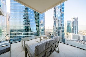 A modern balcony with a sofa and a chair, offering a city view.