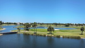 Ein Golfplatz mit Wasserhindernissen, Palmen und blauem Himmel.