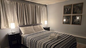 A neatly made bed with striped bedding, a bedside lamp, and a folded towel on the bed.
