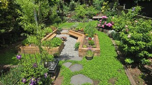 A garden with raised beds, a stone pathway, and various plants.