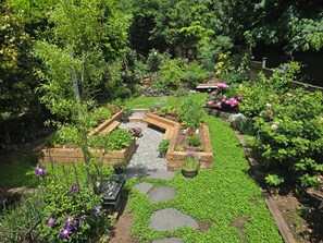 Un giardino con aiuole rialzate, un vialetto in pietra e diverse piante.