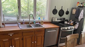 Een keuken met houten kastjes, een roestvrijstalen vaatwasser, een gasfornuis en een koelkast.