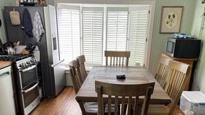 Een keuken met een eettafel, stoelen, een koelkast, een oven en een magnetron.