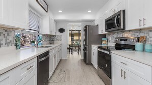 A modern kitchen with white cabinetry, stainless steel appliances, and a tiled backsplash.