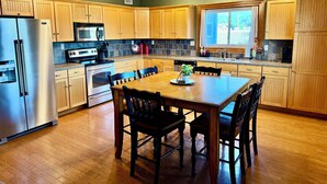Una cocina moderna con armarios de madera, electrodomésticos de acero inoxidable y un comedor con mesa y sillas de madera.