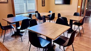 Un salón de conferencias con una gran mesa, varias sillas, una alfombra y un televisor en la pared.