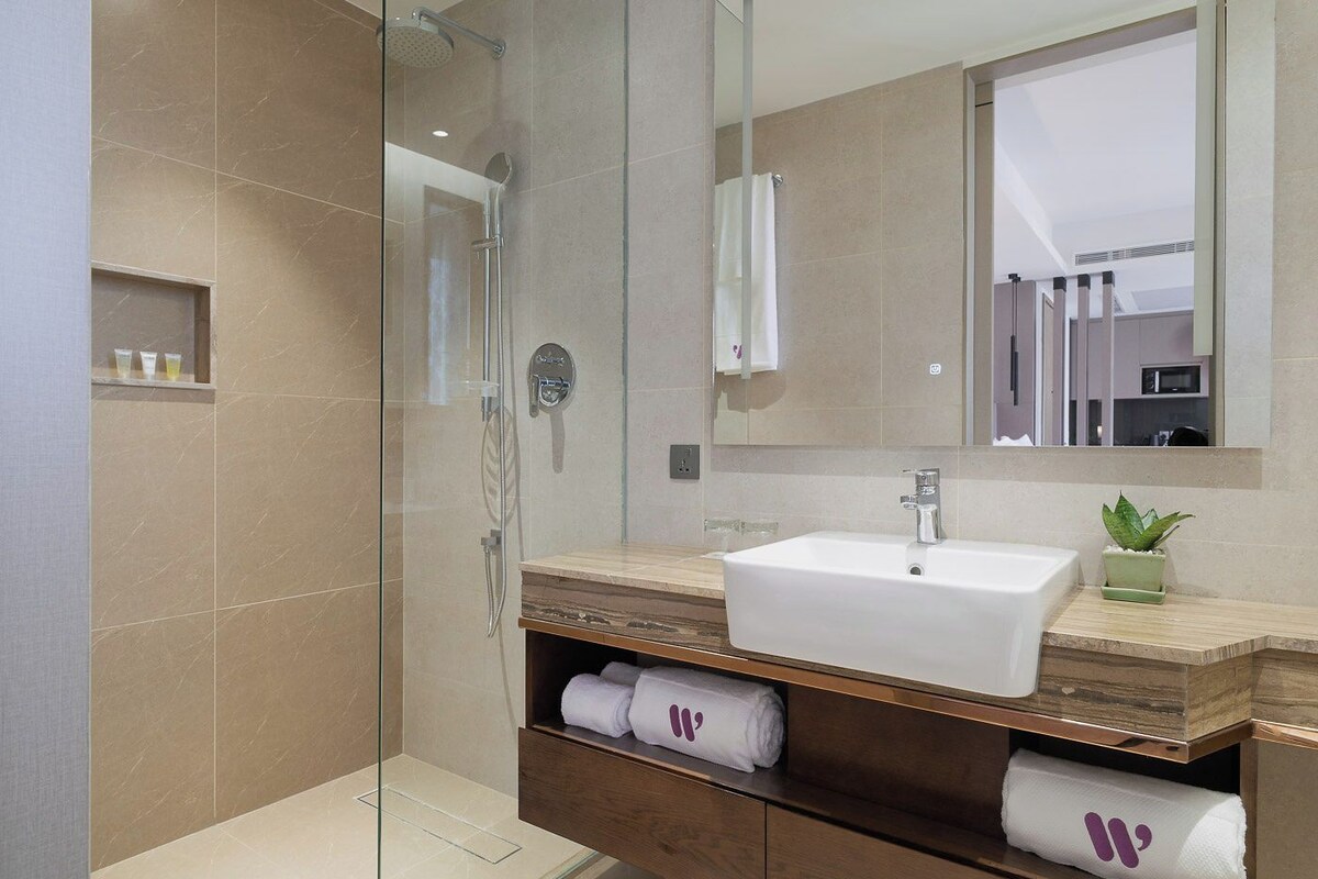 A modern bathroom with a glass-enclosed shower, a white sink, and a wooden vanity.
