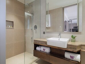 A modern bathroom with a glass-enclosed shower, a white sink, and a wooden vanity. - W Residence Living (Dhaka)
