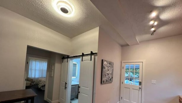 Um quarto espaçoso com piso de madeira, uma mesa de jantar e uma porta que dá para outro cômodo.