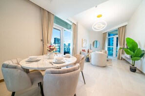 A modern living room with a dining area, large windows, and a city view.