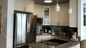 A modern kitchen with a central island, stainless steel appliances, and pendant lighting. - Cozy studio in Waikiki  across the street from Waikiki Beach (Honolulu)