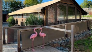 Une terrasse en bois dotée d’une structure en verre abritant des flamants roses.