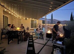 An outdoor patio with a covered seating area, a fire pit, and a dining setup.