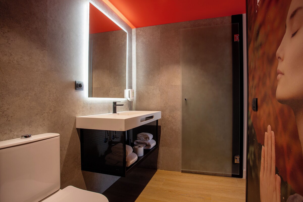 A modern bathroom with a white sink, a mirror, and a towel rack.