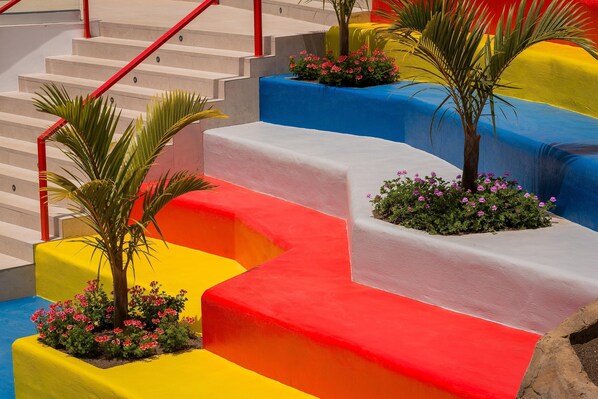 A staircase with steps painted in bright colors and small plants at the base of each step. - Sholeo Lodges Maspalomas (San Bartolomé de Tirajana)