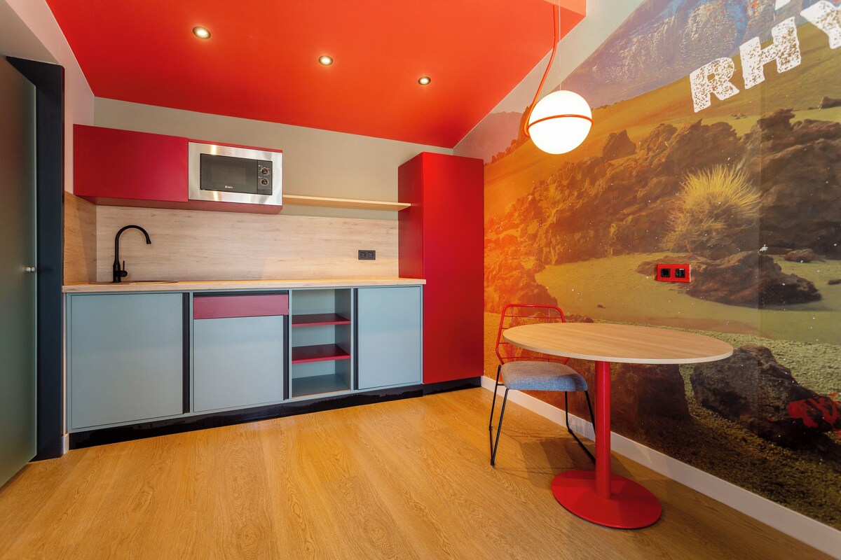 A modern kitchen with a microwave, cabinets, and a red ceiling.