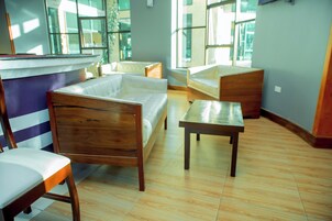 A room with a wooden bed, a wooden chair, a wooden table, and a white sofa.