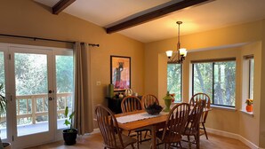 A dining area with a wooden table and chairs, a chandelier, and a painting on the wall.