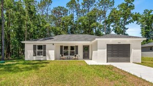 A single-story house with a garage, a front porch with a table and chairs, and a well-maintained lawn.