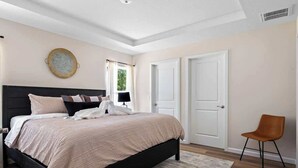 A bedroom with a bed, a chair, and a door.