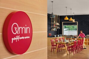 A restaurant interior with a red logo, wooden furniture, and a black brick wall. - Ginger Udaipur, Shastri Circle (Udaipur)