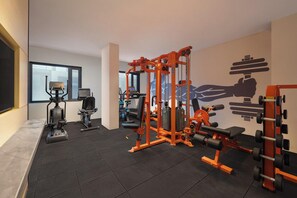 A gym with various exercise equipment, including a squat rack, bench press, and cardio machines. - Ginger Udaipur, Shastri Circle (Udaipur)