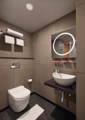 A modern bathroom with a toilet, sink, and mirror. - Ginger Udaipur, Shastri Circle (Udaipur)