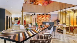 A modern interior with a long dining table, comfortable seating, a TV, and a staircase with a unique design. - Ginger Udaipur, Shastri Circle (Udaipur)