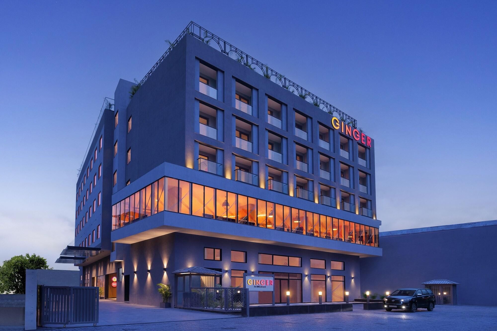 Un hôtel moderne, reconnaissable à son grand panneau « GINGER », doté de nombreux balcons et d’une façade bien éclairée.