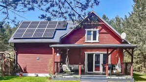 A red house with a solar panel roof, a covered porch, and a small garden. - Beautiful home in Karsin with sauna (Karsin)