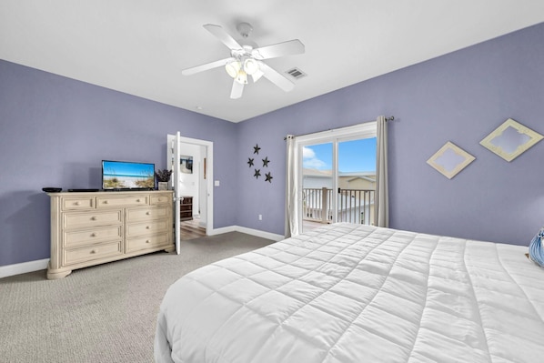 A bedroom with a bed, dresser, ceiling fan, and a view of the outdoors through a window. - Grouper Therapy (Santa Rosa Beach)