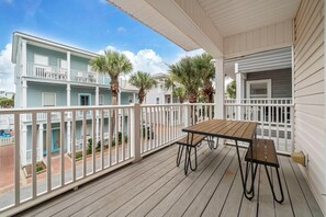 A wooden deck with a table and benches, overlooking a residential area with houses and palm trees. - Grouper Therapy (Santa Rosa Beach)